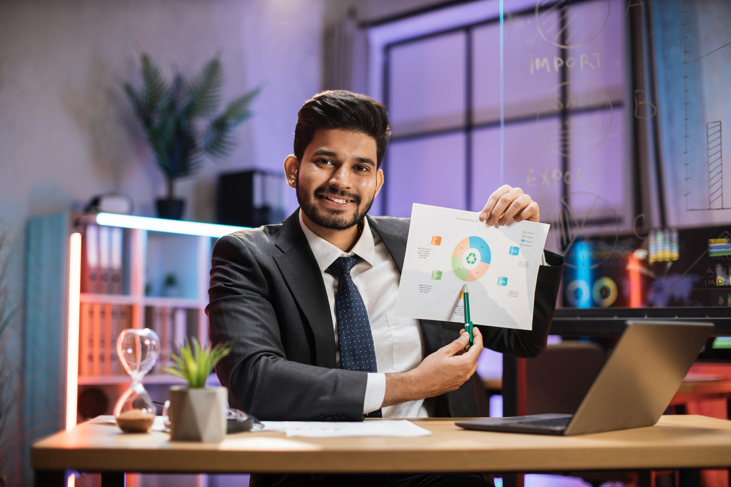 Confident arab financial expert office worker in suit working on laptop, showing paper report